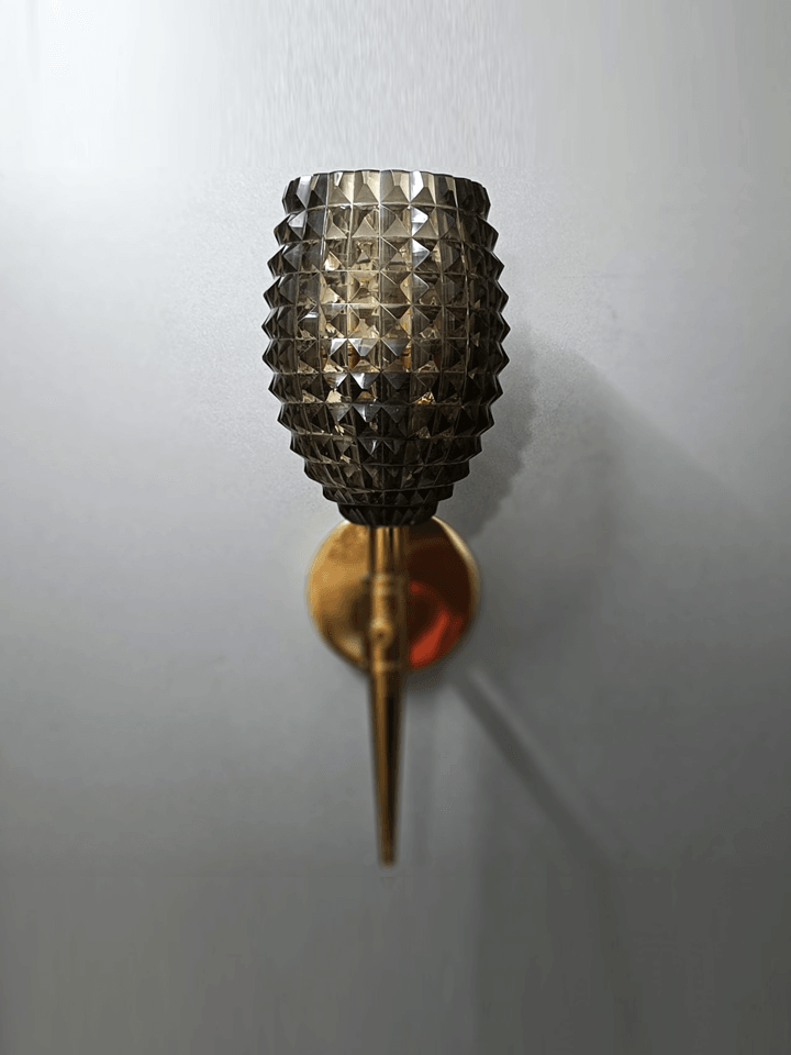 Close-up of smoky black, oval diamond-cut crystal glass shade of wall lamp.