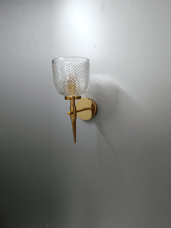 Diamond-cut crystal glass wall lamp with gold PVD finish, perfect for bedroom ambiance.