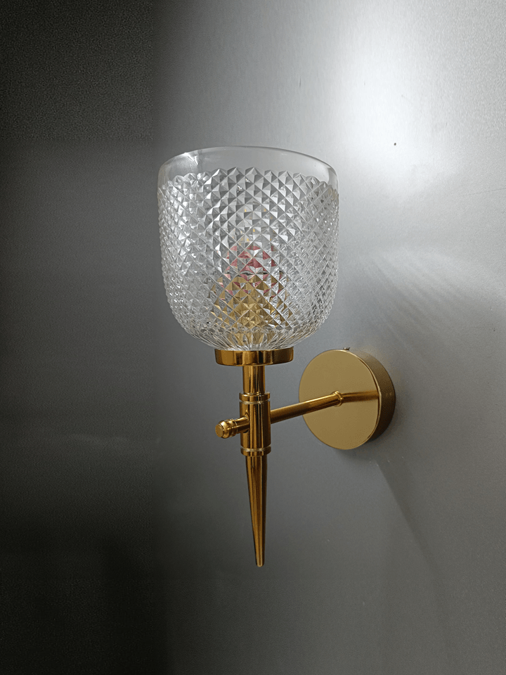 Gold PVD wall sconce with clear crystal glass, hand-cut for a dazzling display in the bedroom.