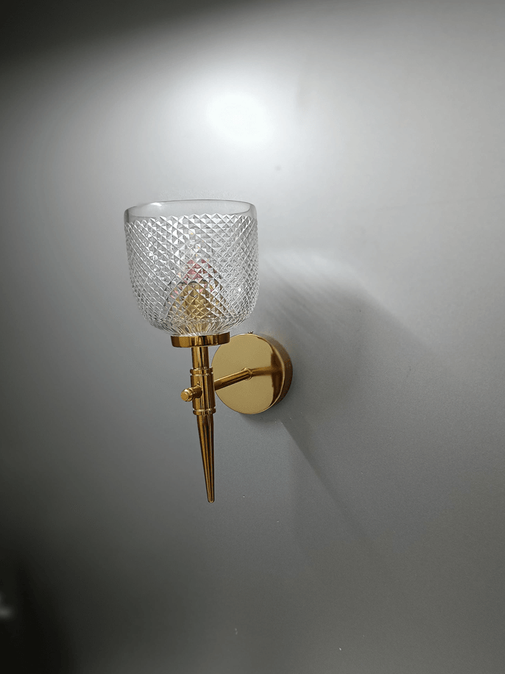 Luxurious gold wall lamp featuring hand-cut crystal glass for a touch of brilliance in the bedroom.