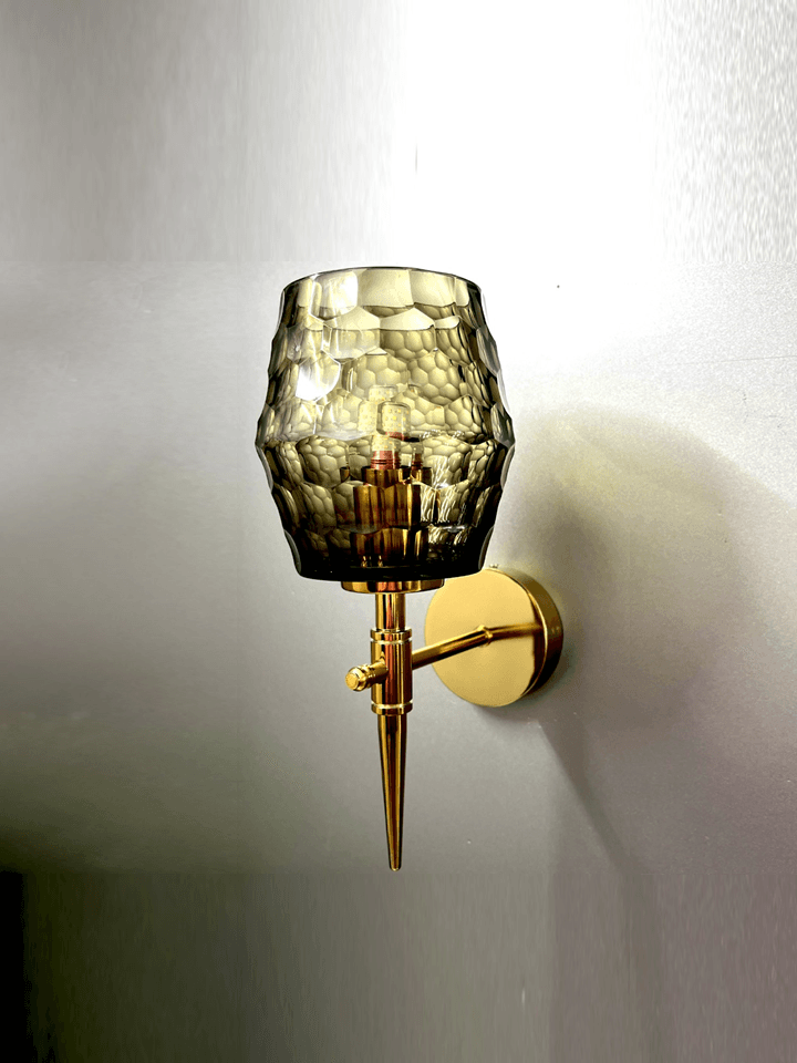 Modern wall sconce featuring black smoky glass, a gold PVD finish, and captivating diamond cuts.