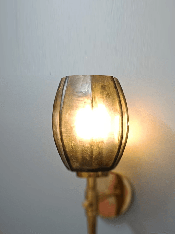 Gold wall light illuminating artwork in a luxurious living room (India).