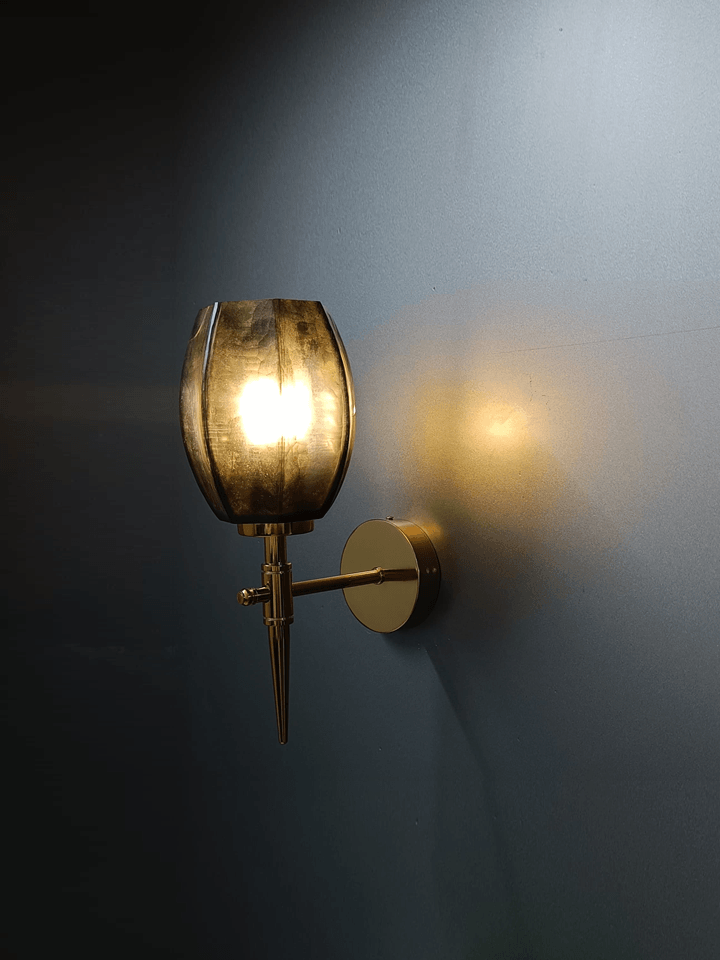 Gold wall light casting a beautiful pattern of light on a living room wall (India).