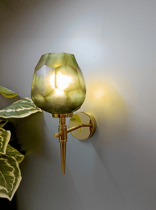 Luxurious gold PVD wall light design with asymmetrical dark green, diamond-cut glass.