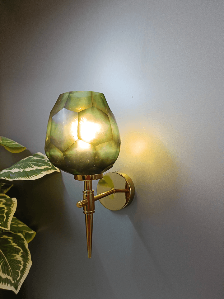 Gold PVD wall light showcasing an asymmetrical, hexagonal diamond-cut dark green glass shade.