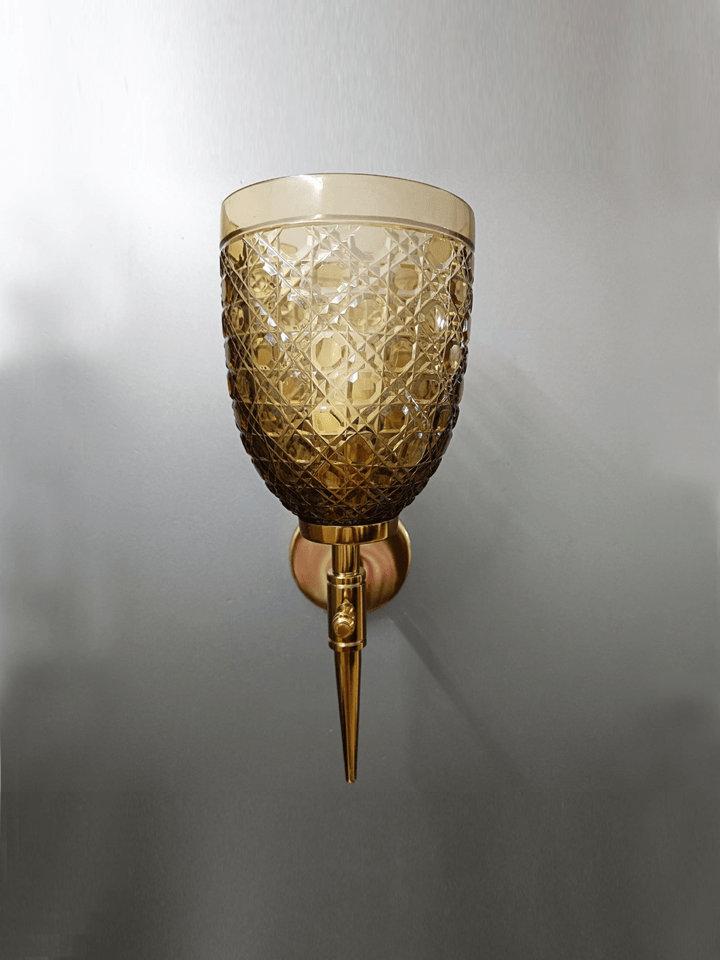 Sitting room wall lamp featuring diamond-cut crystalline champagne glass and gold PVD finish.