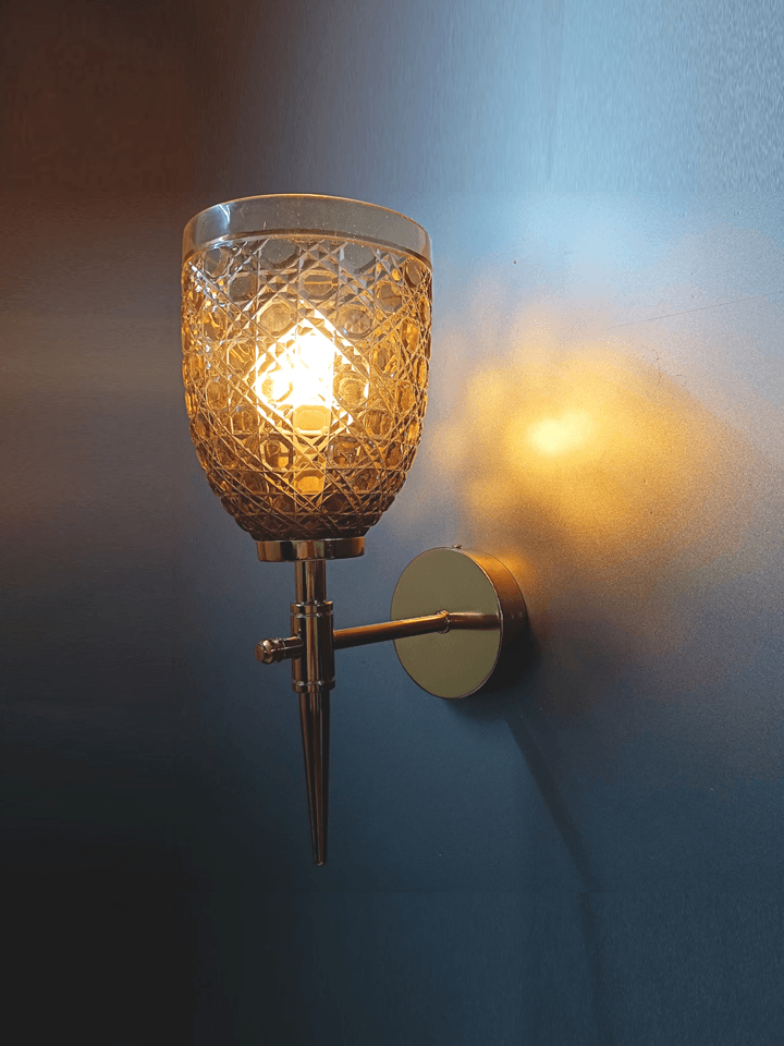 Sitting room wall sconce featuring a gold PVD finish and hand-cut champagne glass for a touch of elegance.