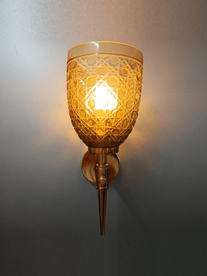 Enhance your sitting room decor with this gold PVD wall lamp and its exquisite, diamond-cut champagne glass.