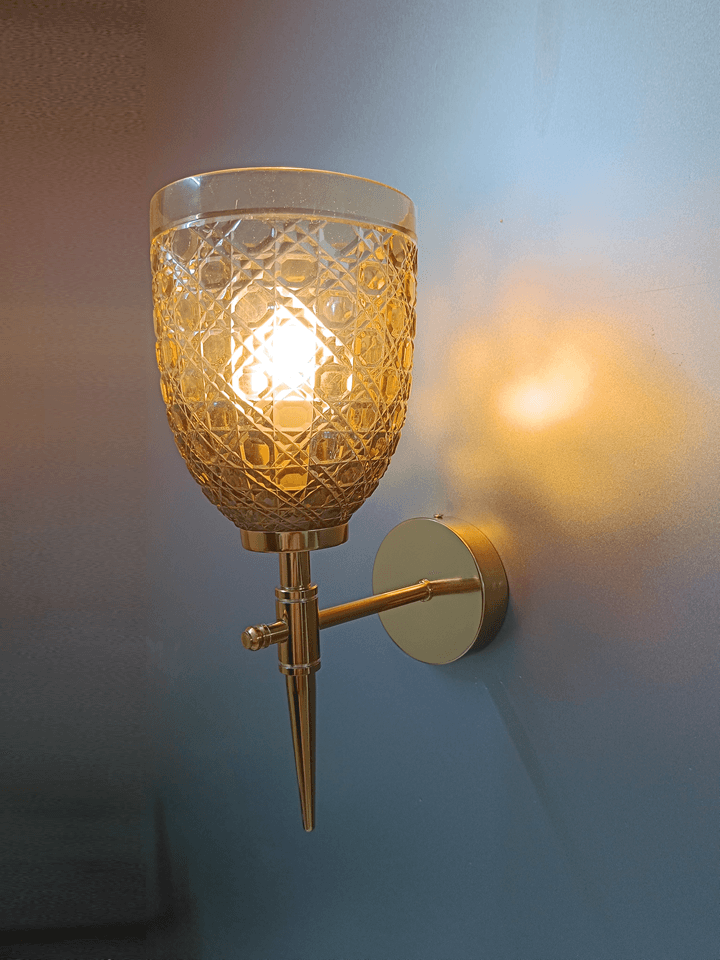 Gold PVD wall sconce with hand-cut champagne glass, casting a warm glow in your sitting room.