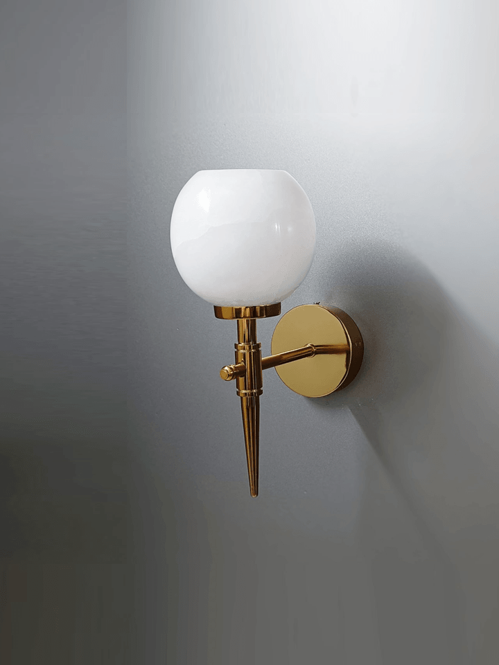 Warm and inviting light from a gold wall sconce with marble shade (Indian crafted).