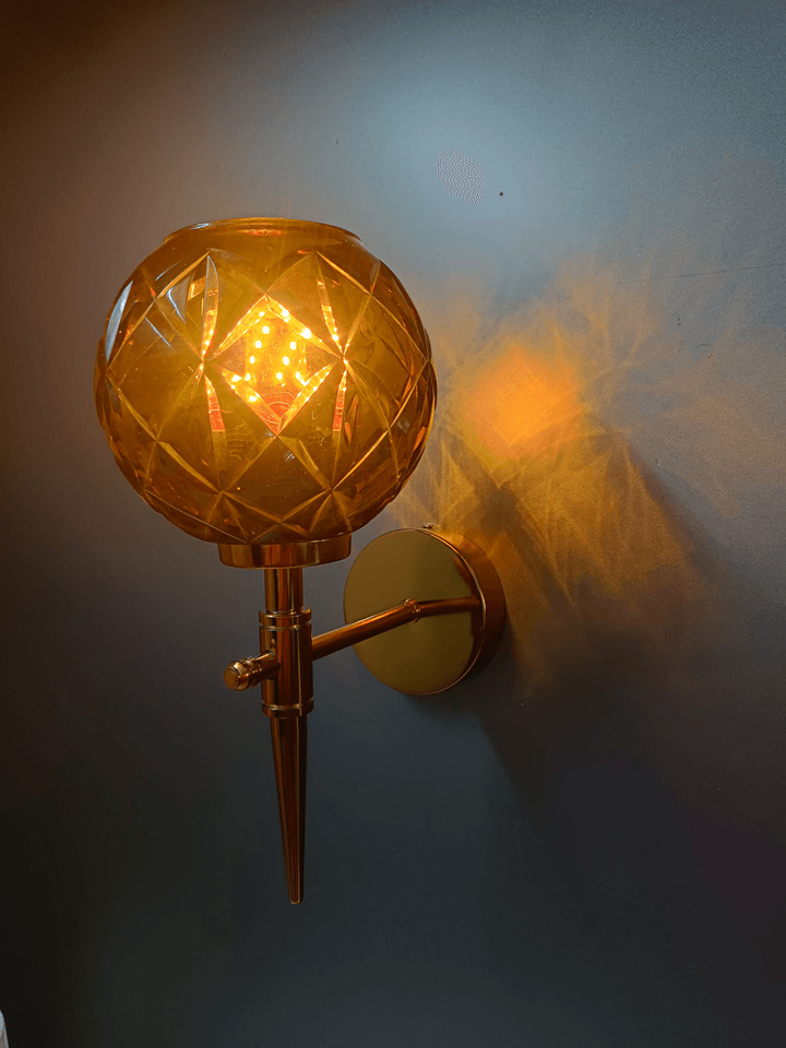 Long-lasting style meets captivating light with this gold PVD wall lamp and amber crystal glass shade (India).