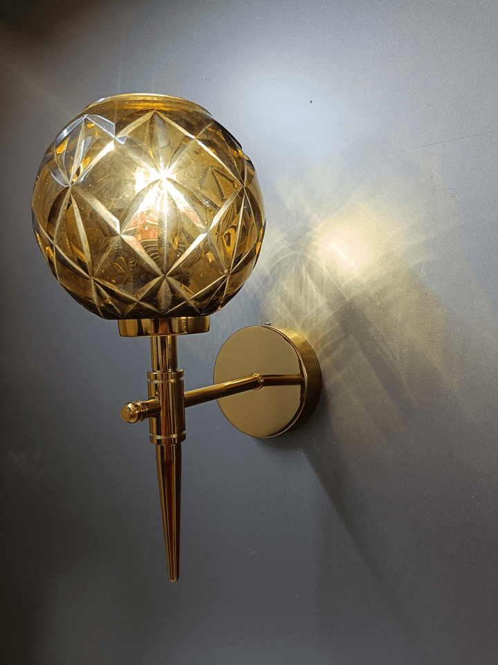 Enhance your bedroom ambiance with the warmth and sparkle of this gold PVD wall lamp and amber crystal glass.