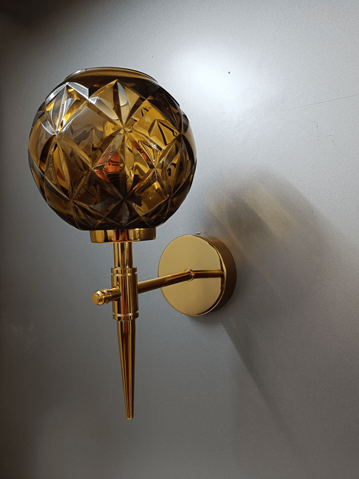 Diamond-cut amber crystal glass wall lamp with gold PVD base, ideal for bedrooms (India).