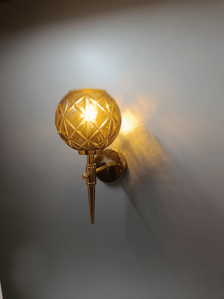 Modern bedroom wall sconce with sparkling amber crystal glass and gold PVD finish.