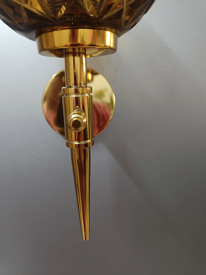 Illuminate your bedroom with the brilliance of this gold PVD wall lamp and its hand-cut amber crystal glass.