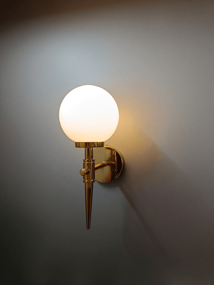 Glamorous wall sconce: gold PVD finish with a luminous frosted opal glass ball.