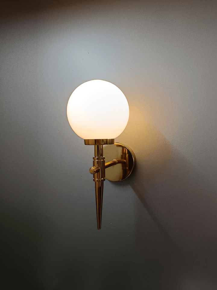 Gold PVD wall light featuring a frosted opal glass ball, resembling a luminous ice ball.