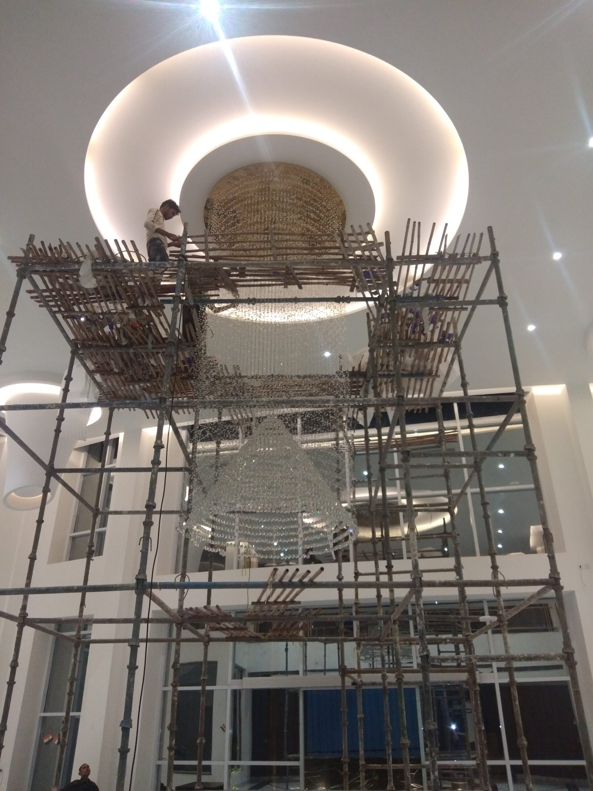 Double-height clubhouse chandelier in Purvanchal Royal City viewed across the lobby