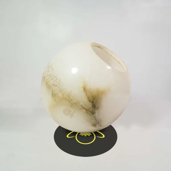 Alabaster ball tilted to show its hand-finished opening and honey-brown stone veins