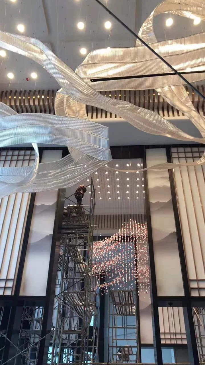Installation-stage ribbon chandelier with scaffolding in the StayWell Kerala hotel project
