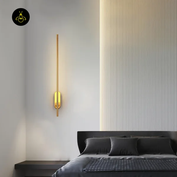 Brass wall sconce beside a bed with a dark grey headboard and a ribbed panel wall