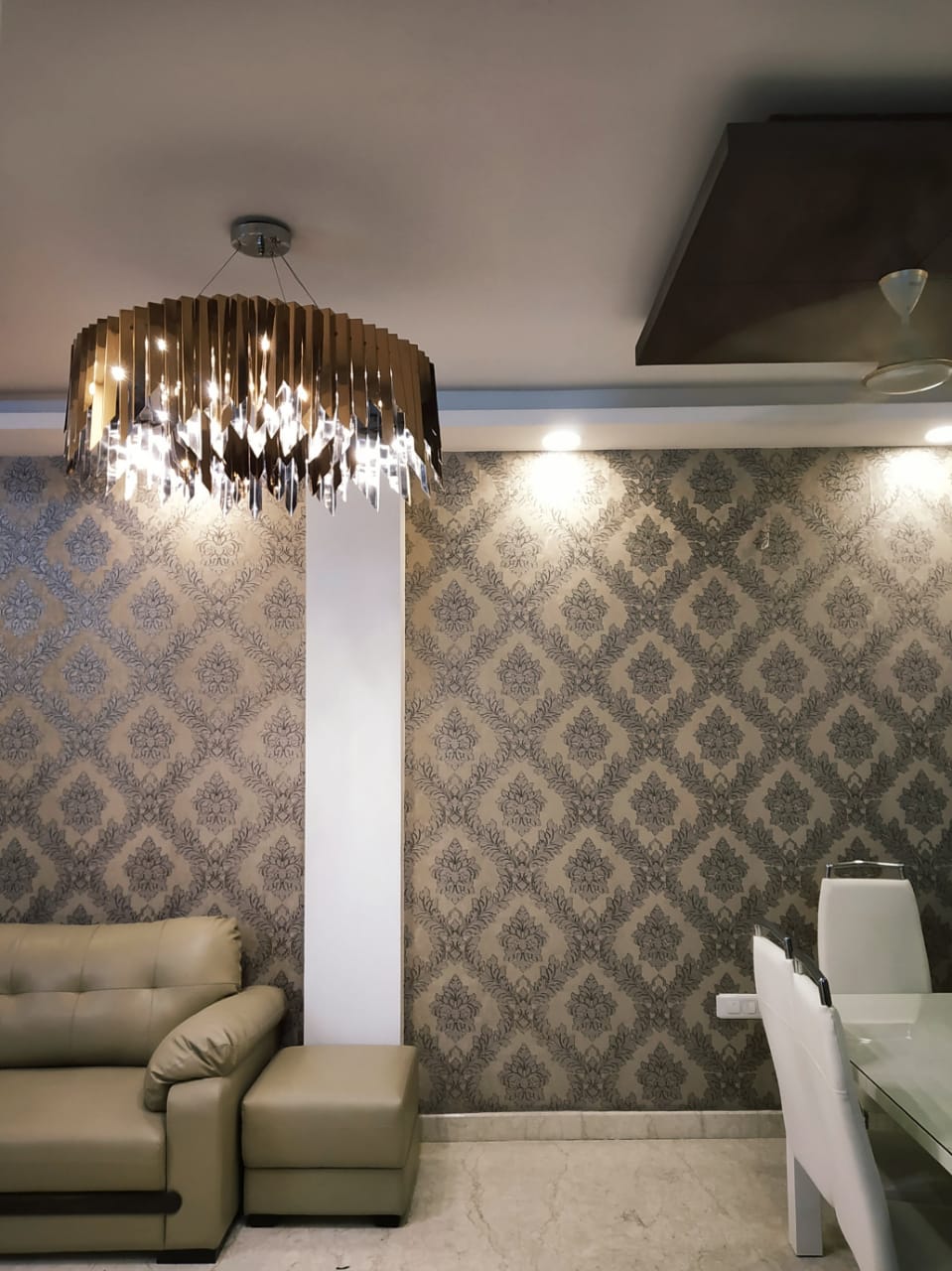 Residential round chandelier with blade-like metallic edge details above a Delhi living room