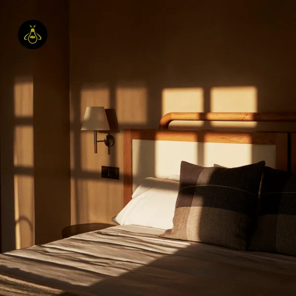 Fabric wall light beside a wooden bed headboard in evening sunlight in a bedroom