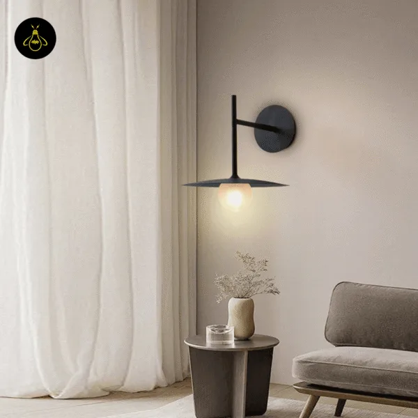 Black wall lamp lit above a side table and armchair in a living room