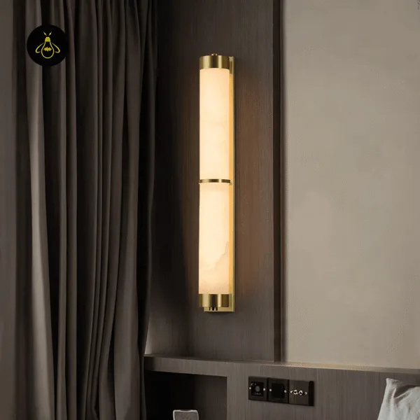 Alabaster wall light glowing beside a bed next to dark curtains and a wood-panel headboard wall