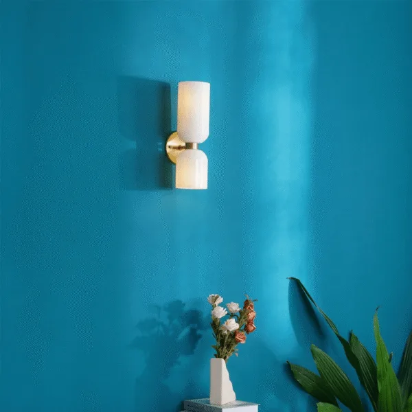Wall sconce for bedroom with opal borosilicate glass shades on a teal wall above a vase of flowers