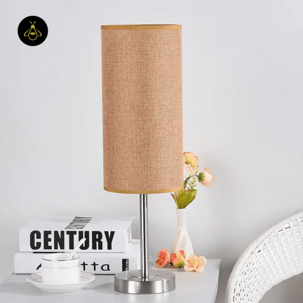 Brown fabric table lamp with linen shade on a bedside table with books