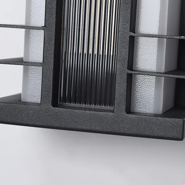 Close-up of the outdoor wall sconce: matte black stainless steel fins, fluted acrylic centre panel and textured frosted acrylic side panels