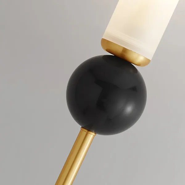 Close-up of the polished black marble sphere on a marble wall sconce, with brass-finish collar and rod