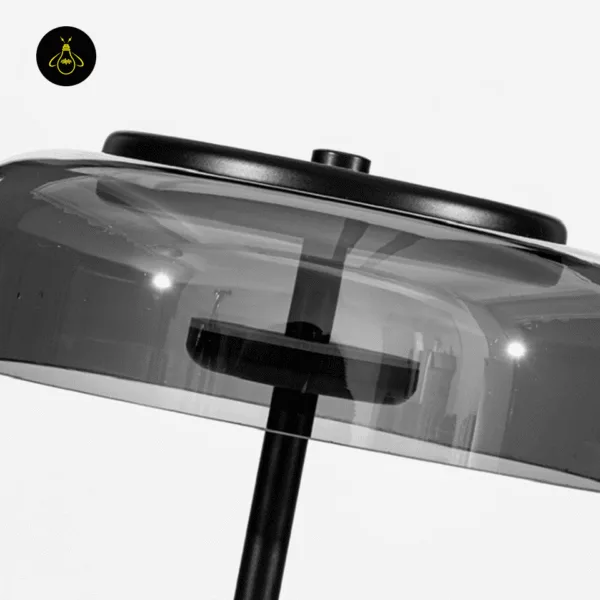 Close-up of the integrated LED and smoked borosilicate glass dome on a black glass table lamp