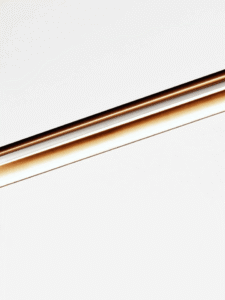 Close-up of brushed stainless steel finish on linear LED chandelier with warm glow