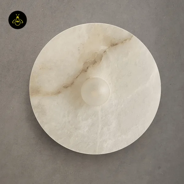 Close-up of the disc wall light: white alabaster with a brown vein and the round opal lens at its centre