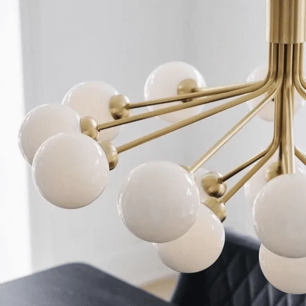 Close-up of opal borosilicate glass globes on brushed-brass arms of a glass globe chandelier
