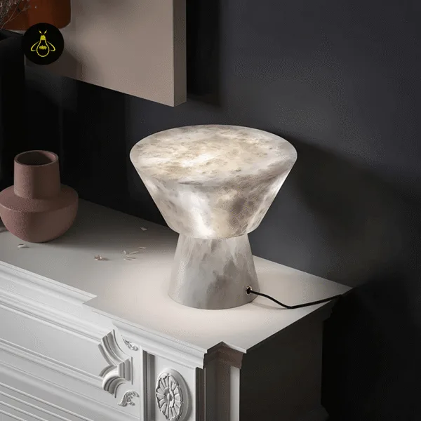 Alabaster mushroom table lamp glowing on a white carved sideboard against a dark wall