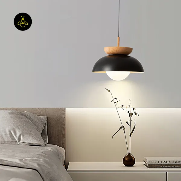 Black and teak dome pendant light hanging beside a bed over a white bedside table with a vase and books