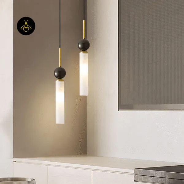 Two marble pendant light drops glowing warm over a white kitchen counter