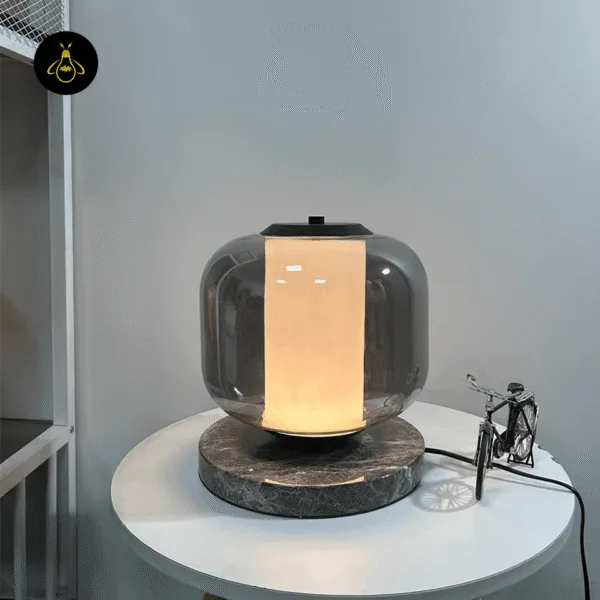 Contemporary black marble table lamp with smoked borosilicate glass shade on an office console
