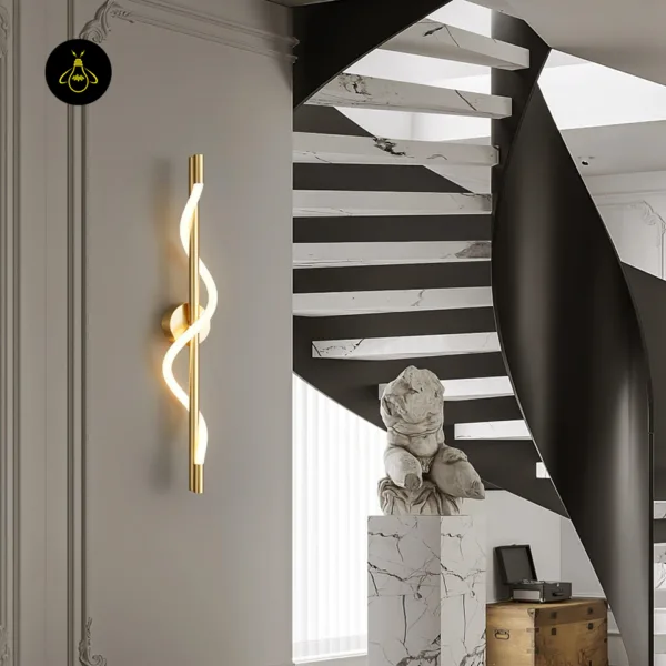 Gold spiral linear wall light lit on a panelled wall beside a spiral staircase