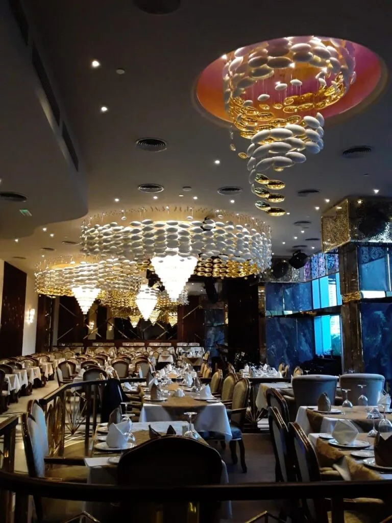 Crystal cone chandelier integrated into a patterned restaurant ceiling in Hyderabad