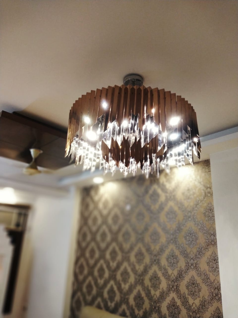 Close view of the custom-made round chandelier showing crystal drops and metallic fins