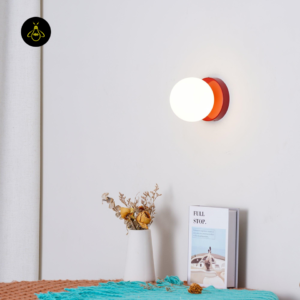 Red glass globe wall sconce mounted above a bedside console for a bedroom accent