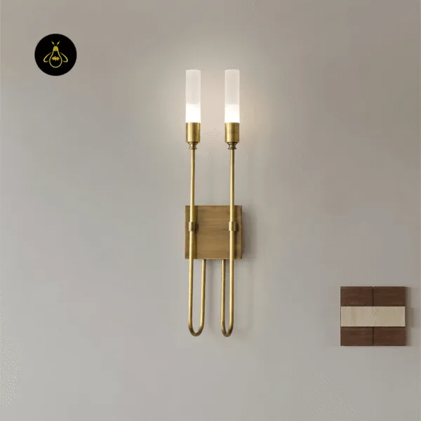 Gold wall sconce glowing on a pale grey wall beside a small wood and stone panel