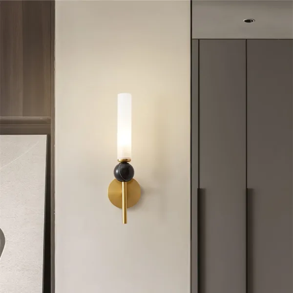 Marble wall sconce lit on a cream wall between wood panels and grey wardrobe doors