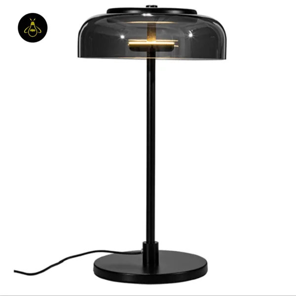 Black glass table lamp casting warm ambient light on a bedroom nightstand