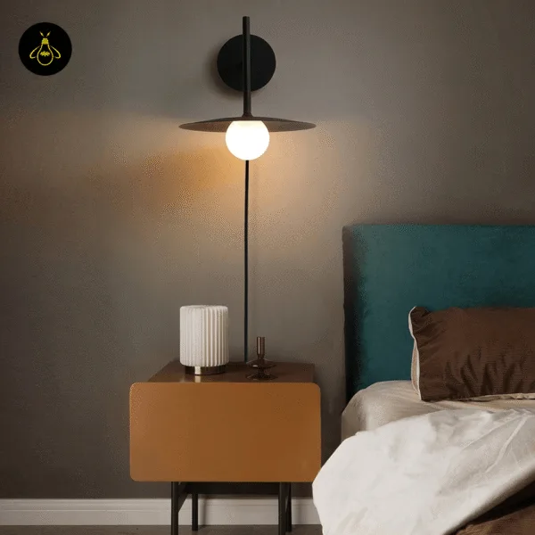 Black wall lamp with a opal borosilicate glass globe above a bedside table next to a teal headboard