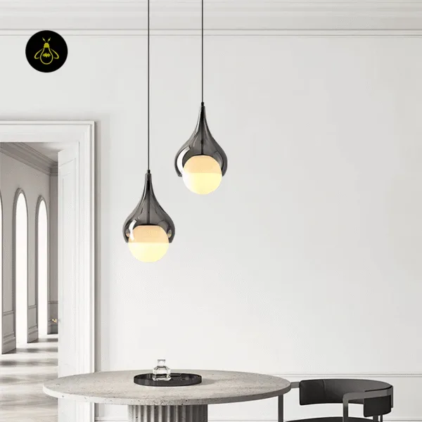 Two hanging bedside lights in smoked glass, hung at different heights over a round stone dining table